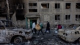 People carry their belongings as they leave their damaged residential building following a strike in Dobropillia, Donetsk region, on March 8, 2025, amid the Russian invasion of Ukraine.